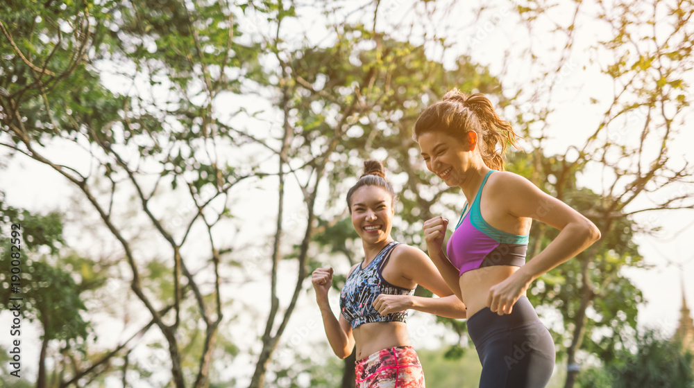 Fototapeta premium Two athletic woman running outdoors. Action and healthy lifestyle concept.Jogging run in park