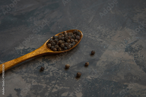 Black pepper on a wooden spoon, copy space