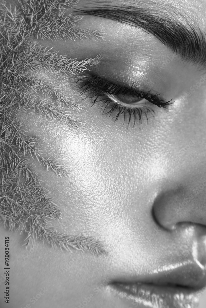 Fototapeta premium Beauty portrait of woman with wet skin and pink branch on her face. Black and white