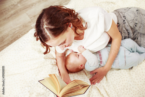 Woman reading a book while brestfeeding a baby on bed photo