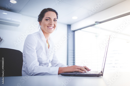 Beautiful brunette female business woman working on her laptop in her office