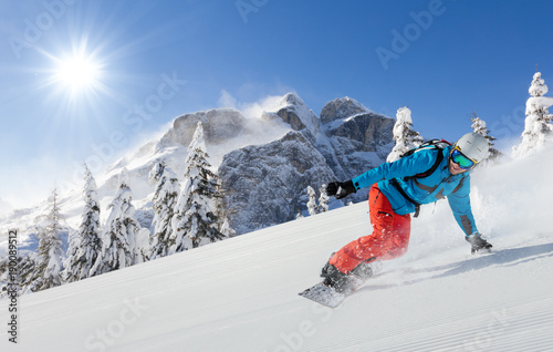 Young man snowboarder running downhill in Alps