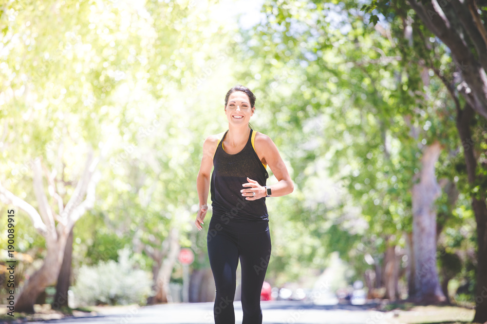 Beautiful brunette female fitness model running / stretching / exercising outside in a leafy and green suburb Beautiful brunette female fitness model running / stretching / exercising outside in a leafy and green suburb