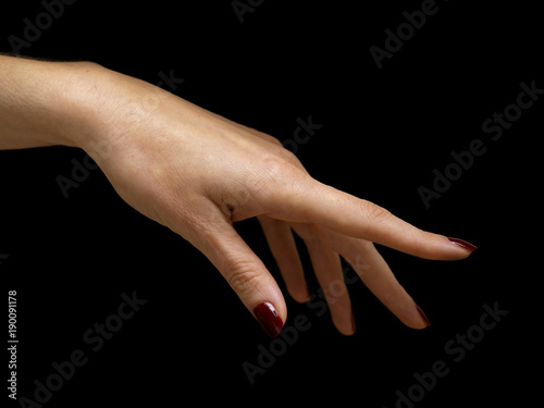 female hand with red nail polish on black background