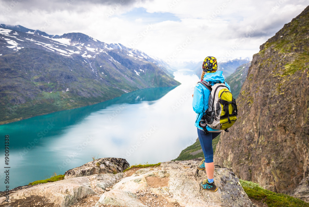 Sport couple hiking on Besseggen. Hikers enjoy beautiful lake and good weather in Norway.