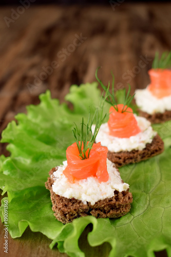 Canape with salmon and cream cheese on a salad leaf