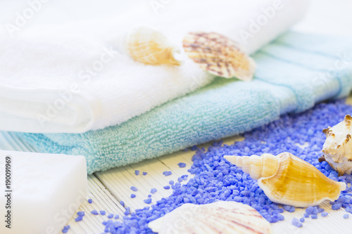 Spa Treatment Concept mock up with natural lavender bath salt, terry towels, a bar of hand made soap and sea shells on a white wooden table