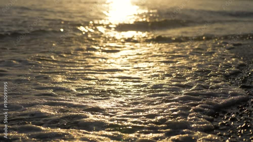 Waves roll on pebble beach with black volcanic sand in sunset time. Sandy beach of the sea. Travel concept. Waves roll on pebble beach with black volcanic sand in sunset time. Sandy beach of the sea. Travel concept.