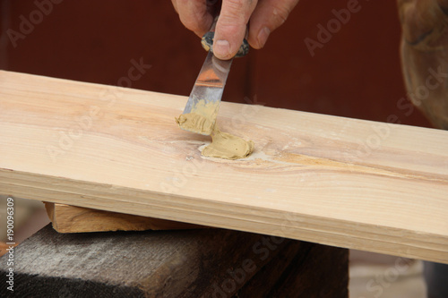 Putty knife in old man's hand. Removing paint from a wood surface. Preparation of boards before impregnation with varnish. Application of putty. Copy space for text