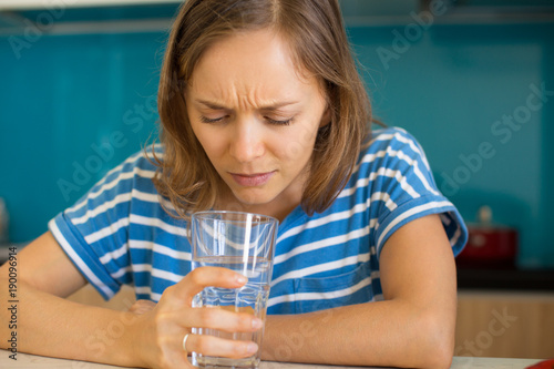 Dissatisfied Woman Looking into Glass of Water photo