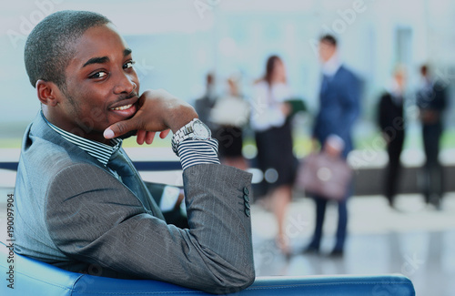 Portrait of smiling African American business man with executives working in background.