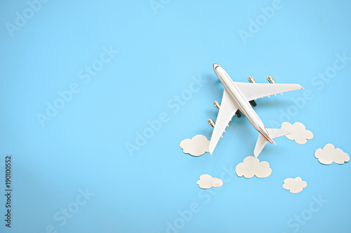 Flat lay design of travel concept with plane and cloud on blue background with copy space.