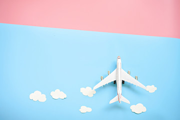 Flat lay design of travel concept with plane and cloud on blue and pink background with copy space.