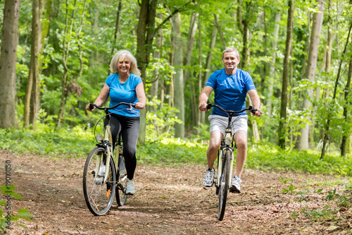 Two senior people cycling in the woods.