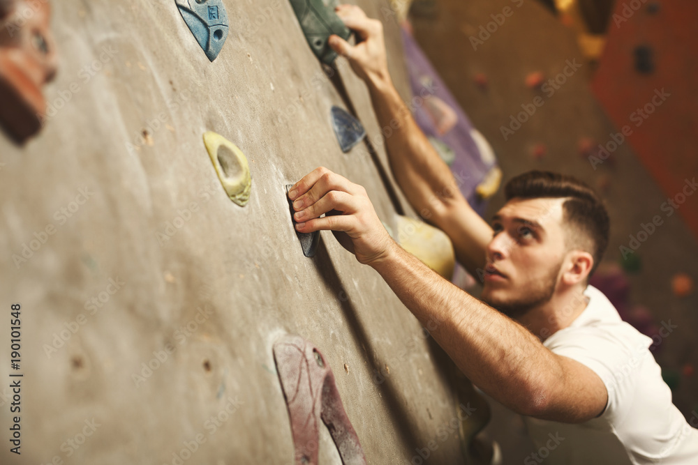 Young man climbing artificial rock wall at gym Young man climbing artificial rock wall at gym