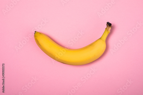 Single banana against pink background. Isolated. Flat lay, top view