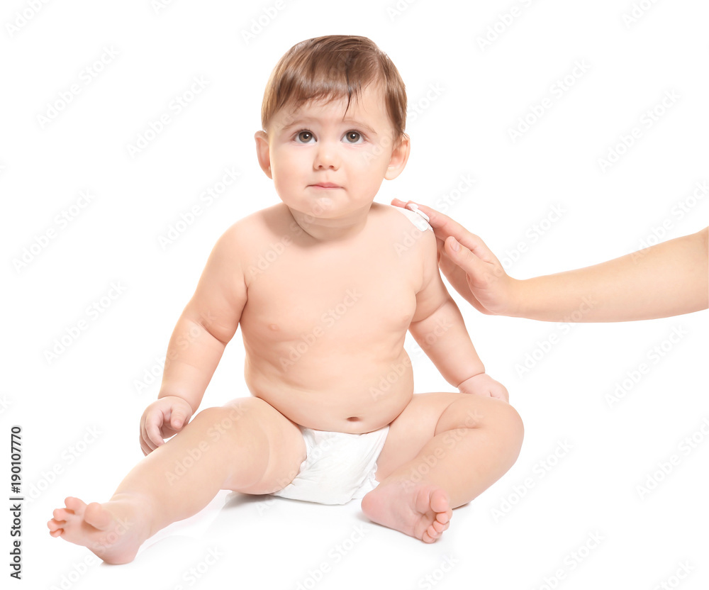 Woman applying body cream on her baby against white background Woman applying body cream on her baby against white background