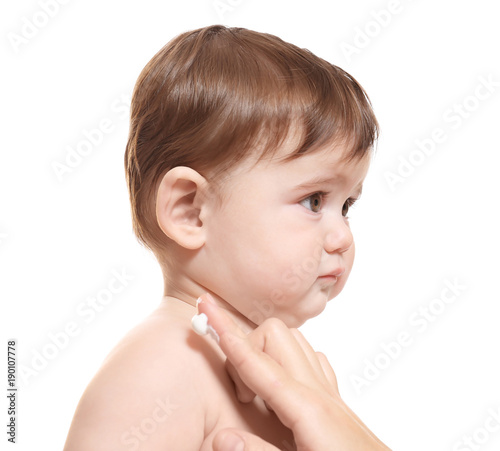 Woman applying body cream on her baby against white background