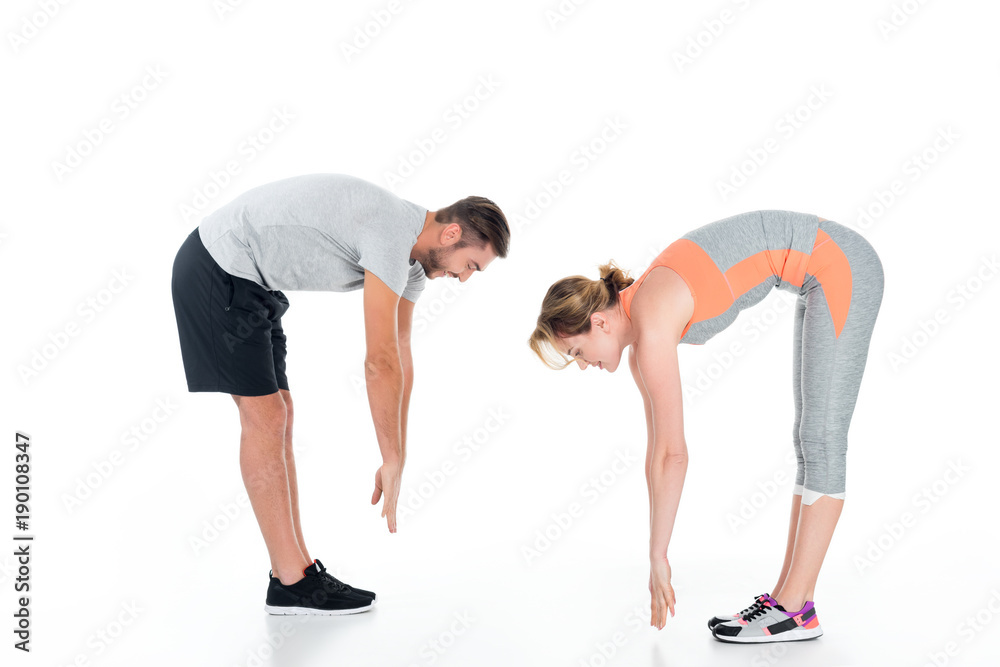 side view of sportive couple warming up before training isolated on white