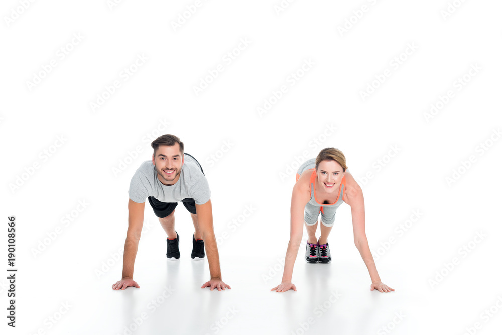 cheerful athletic couple doing push ups together isolated on white