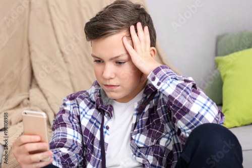 Upset teenage boy with smar...