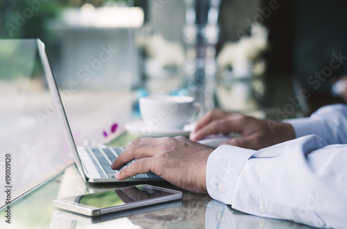 attractive business man hand using laptop working with coffee cup in coffee shop.