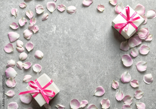 Gift boxes and petals on grey background