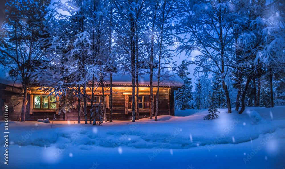 Old wooden forest cabin in winter wonderland scenery at night