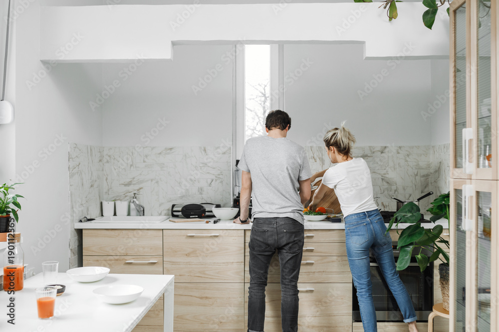 Back view of young couple cooking together. Back view of young couple cooking together.
