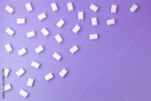 White sugar cubes arranged in diagonal lines on purple background