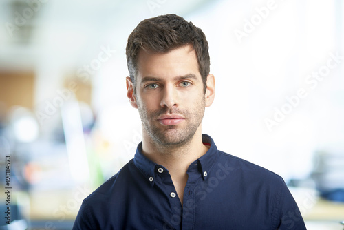 Young professional man. Confident young financial assistant businessman wearing shirt and looking at camera while standing at the office. 