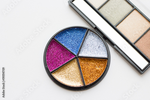 Make Up Beauty Fashion Concept. Bright glitter tinsel palette in a round box and natural eyeshadow palette on white, top view, flat lay