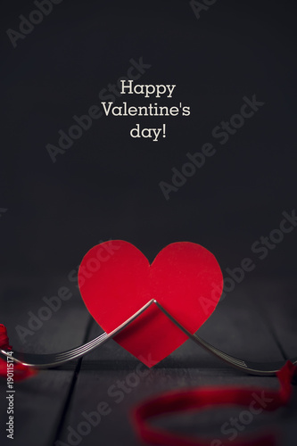 Red paper hearts and a fork with a ribbon. Dark wooden background. Copy space. St. Valentine's Day. photo