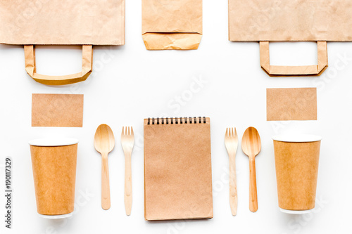 Set of craft bown paper color objects. Paper cup, spoon, fork near paper bag, and notebook top view mock up pattern white background