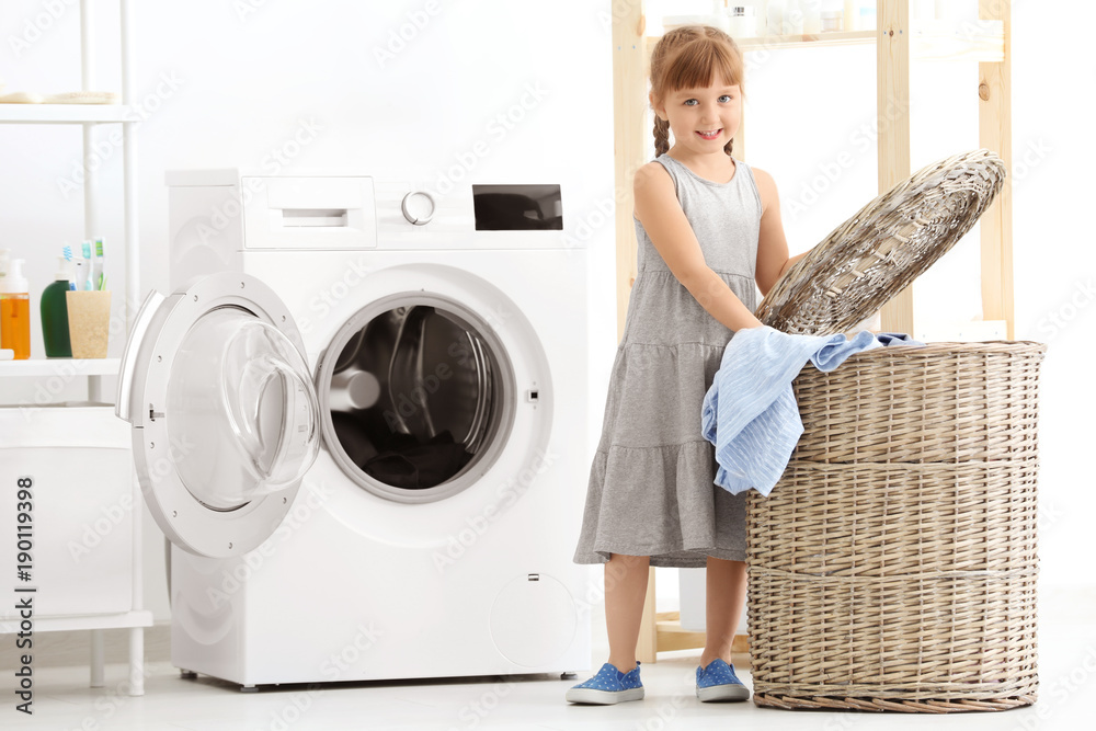Cute little girl doing laundry indoors Cute little girl doing laundry indoors