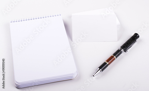 White cards next to notebook and black pen on white background. Isolated. Mockup.