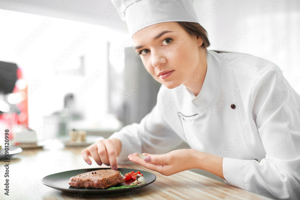 Female chef preparing tasty steak in kitchen Female chef preparing tasty steak in kitchen