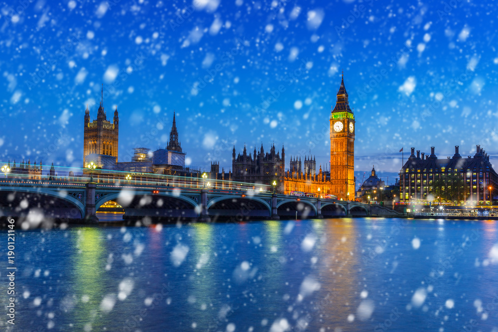 Naklejka premium Big Ben and Westminster bridge on a cold winter night with falling snow, London, United Kingdom