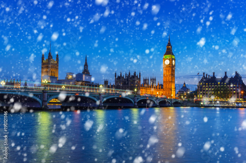 Big Ben and Westminster bridge on a cold winter night with falling snow, London, United Kingdom