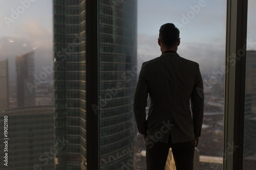 Rearview of a businessman looking out the window at the city.