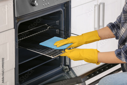 Woman cleaning oven in kitc...