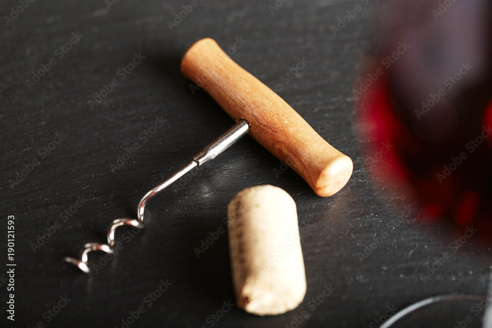 corkscrew next to a glass corkscrew next to a glass