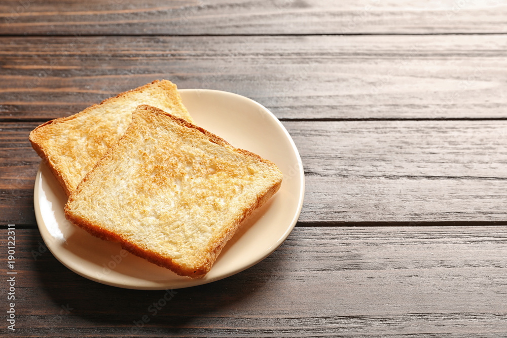 Plate with toasted bread on wooden background Plate with toasted bread on wooden background
