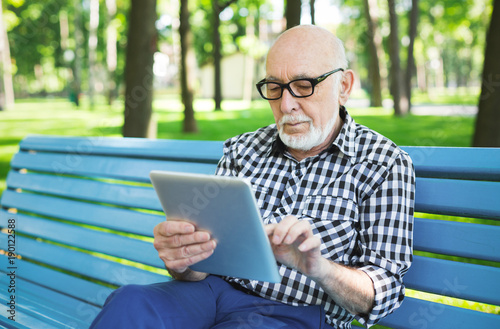 Senior man in casual with digital tablet outdoors