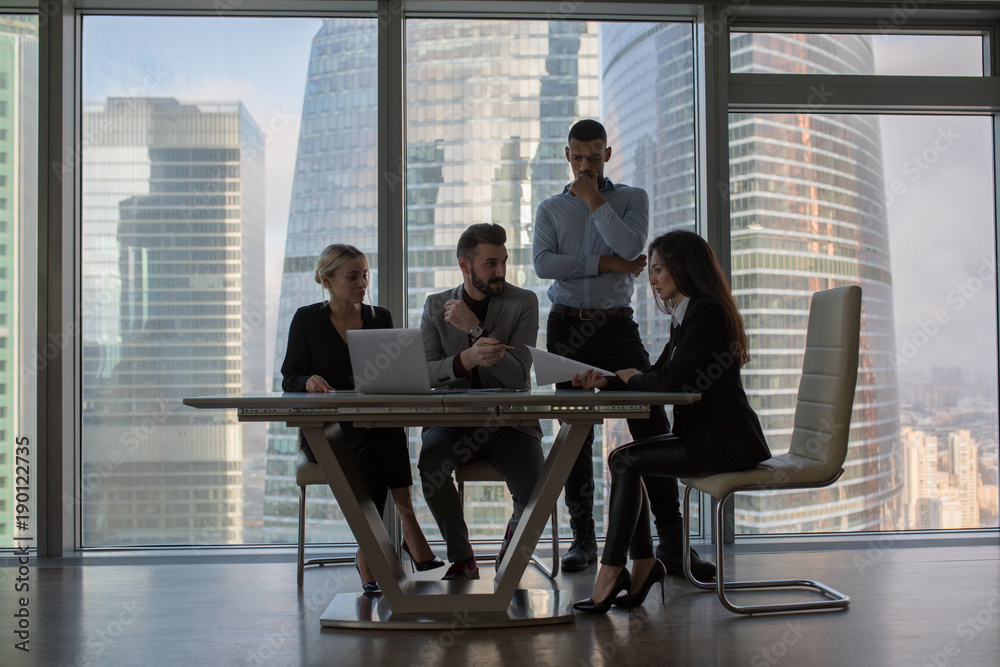 Business people working in an office on a background of panoramic windows. Business people working in an office on a background of panoramic windows.