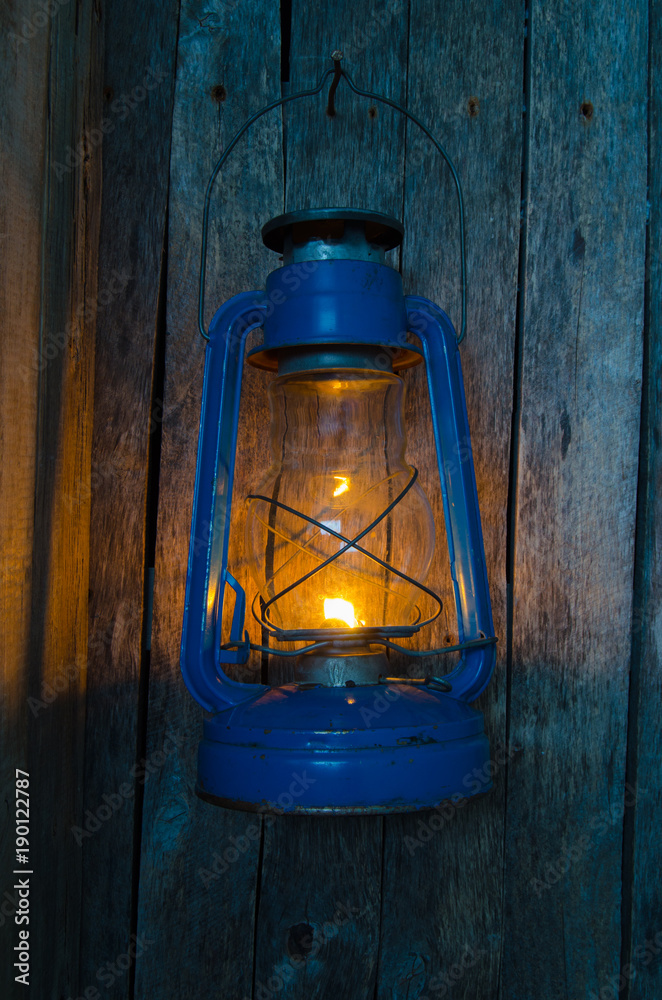 Kerosene lamp illuminates the old wooden wall