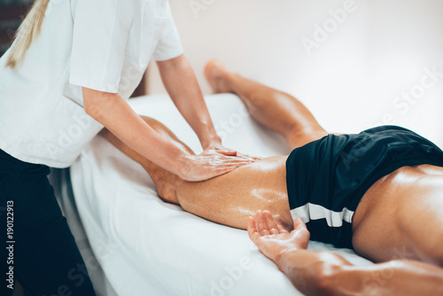 Leg massage. Physical therapyst massaging leg of young male athelete photo