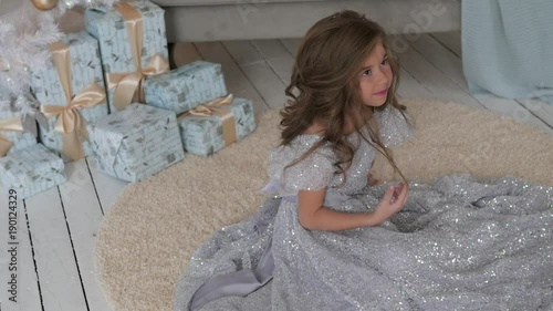 the girl is sitting in a beautiful shiny dress. Christmas interior photo