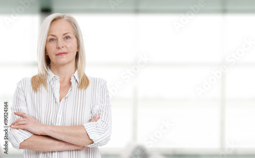 Attractive middle aged business woman with folded arms.