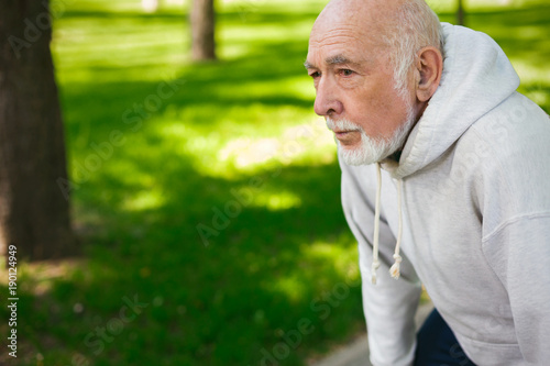 Elderly man running in green park, copy space